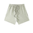 A light sage green pair of shorts with elastic waistband and drawstring displayed on a white background