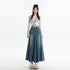 A woman posing in pastel striped crop cardigan and high-waisted denim maxi skirt with center pleat, styled with platform sandals and crossbody bag 