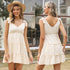 Front and back view of cream-colored babydoll mini dress featuring shoulder ties, V-neckline, empire waist and tiered ruffle design, perfect for summer