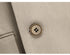 Detailed shot of premium suit button with decorative stitching on beige fabric