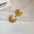 Gold Twisted Hoop Earrings – Elegant gold hoop earrings with a layered, twisted wire design, displayed on crinkled paper