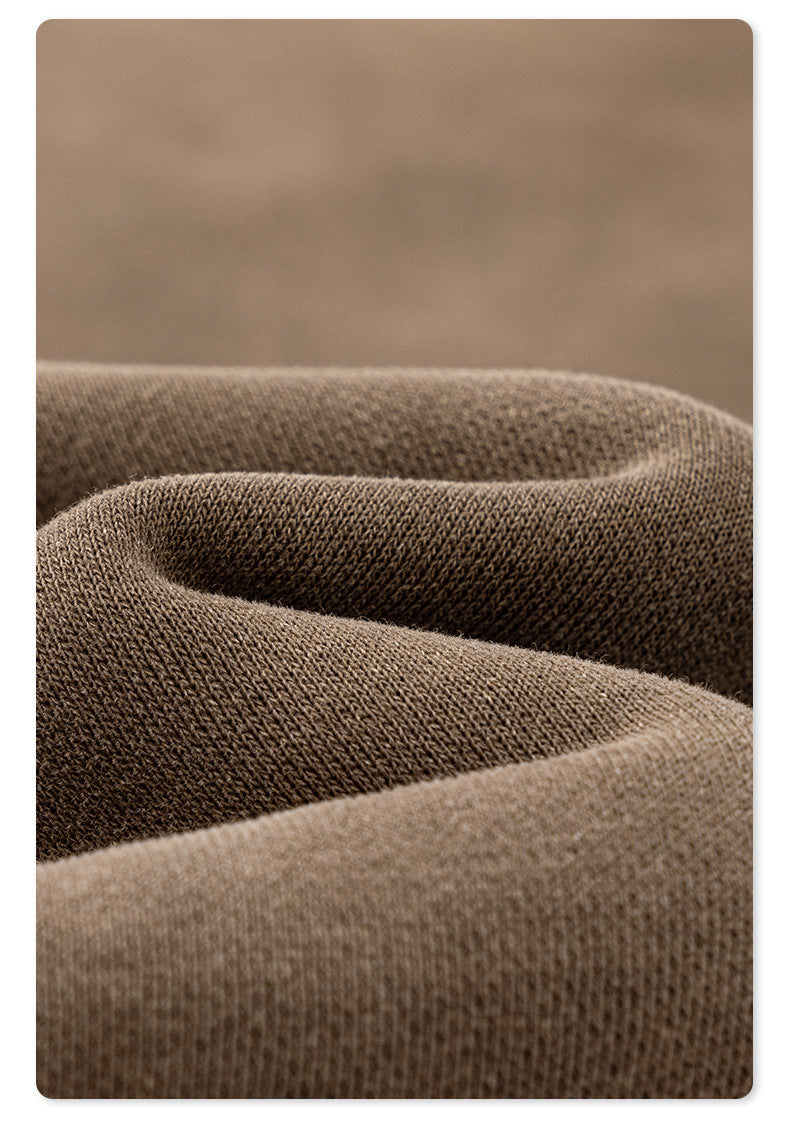 Extreme close-up of taupe cotton sweatpants fabric showing knit texture and subtle color variations