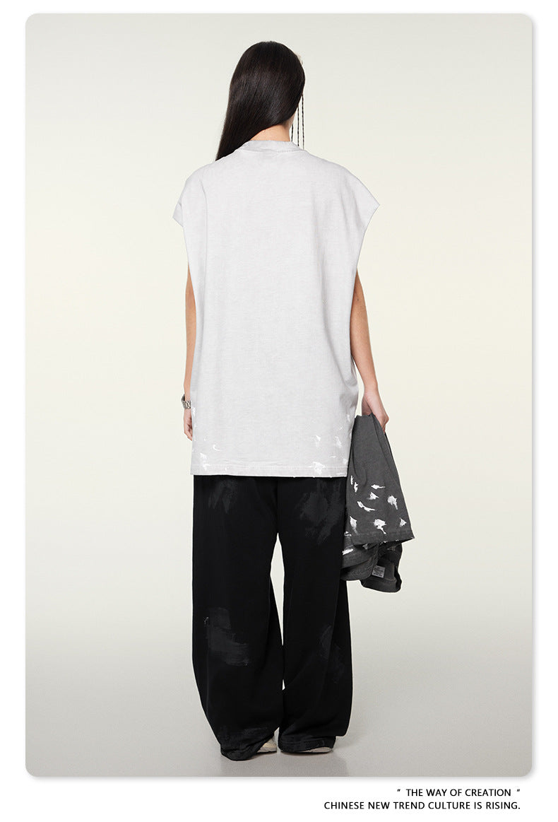 Back view of model in white oversized t-shirt, black wide-leg pants, holding gray jacket against cream background