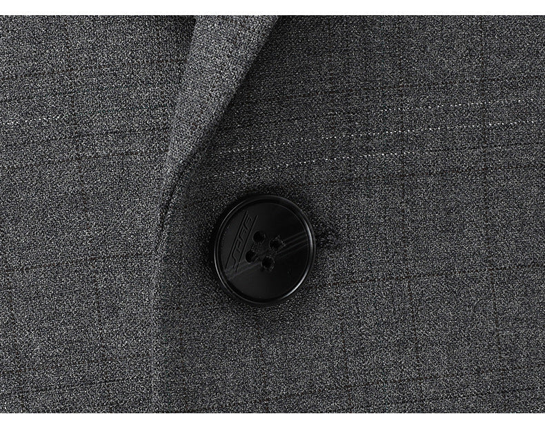 Detail shot of black suit button on gray wool fabric showing texture and stitching of high-quality suiting material