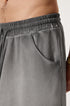 A close-up of elastic waistband on light gray washed cotton shorts showing drawstring and fabric texture detail