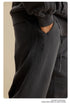 Close-up of hand in pocket of black sweatpants showing textured side panel detail