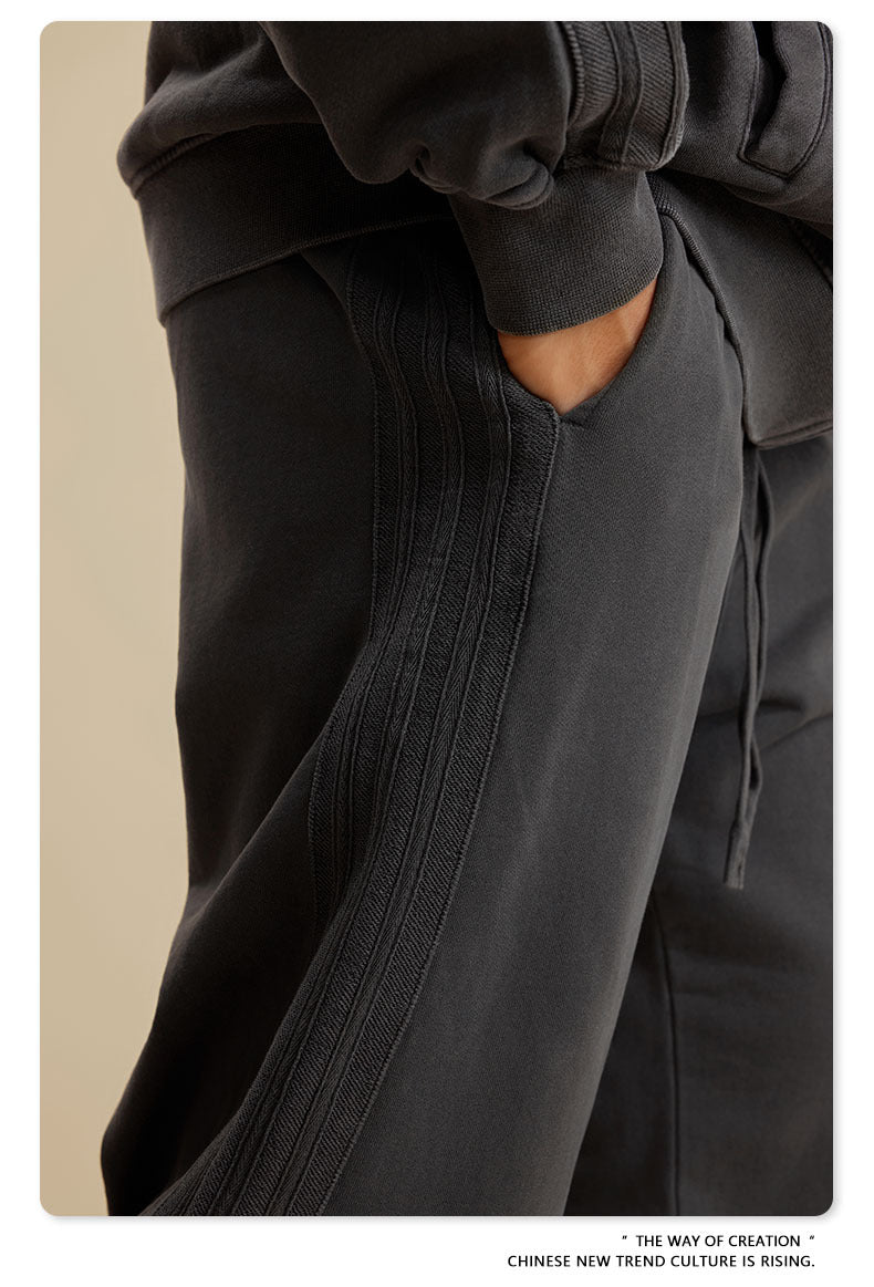 Close-up of hand in pocket of black sweatpants showing textured side panel detail