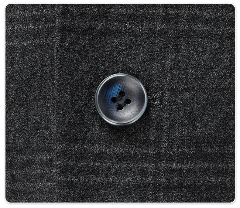 Close-up of dark gray suit button with blue accent against plaid fabric background