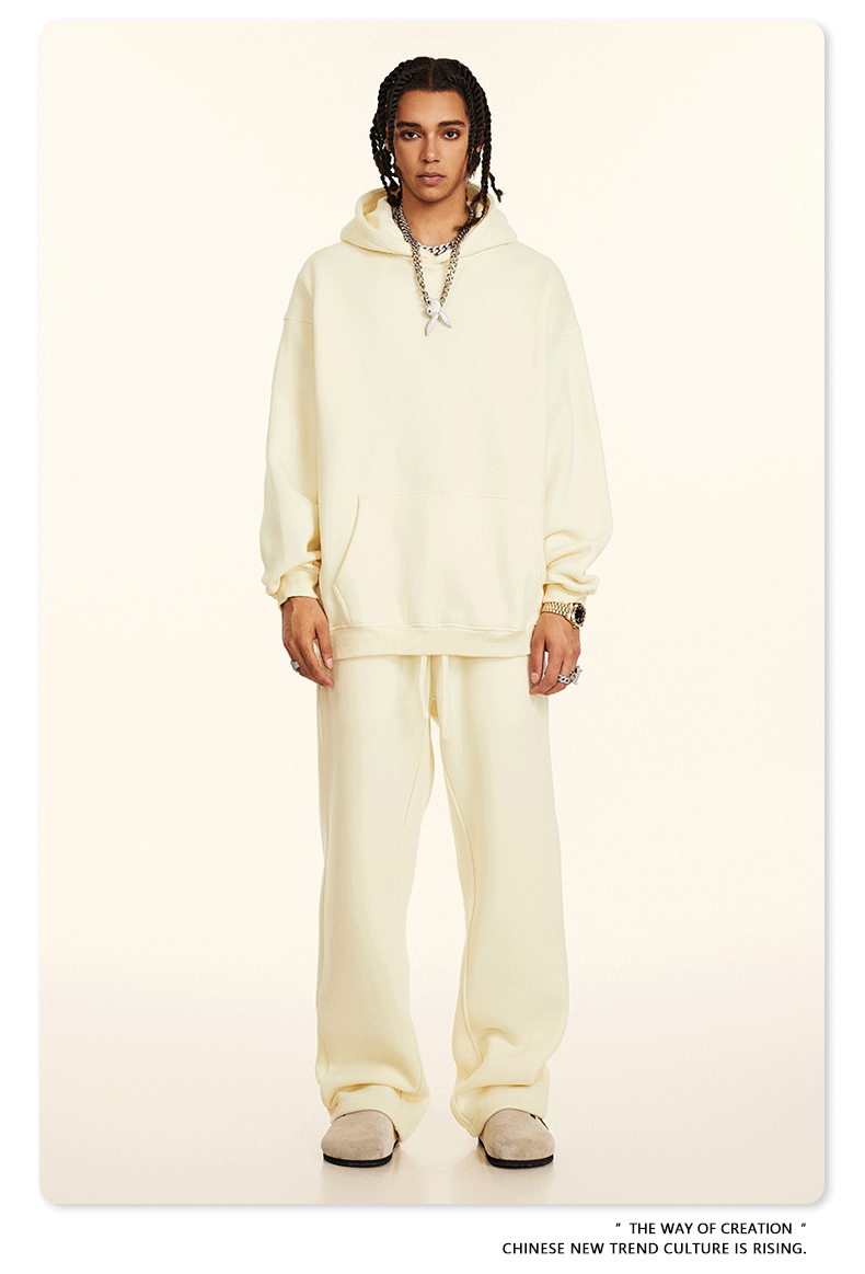 Model in cream hoodie and sweatpants set with silver chain necklace and beige slip-on shoes