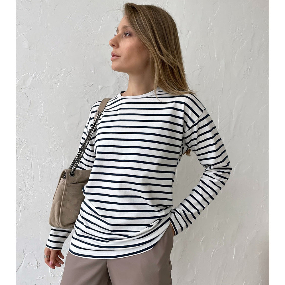 Woman wearing white and navy striped long-sleeve top with beige pants and tan shoulder bag