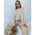 Woman in white and brown striped top and beige pants, holding dried flowers