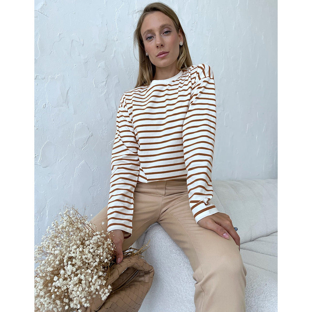 Woman in white and brown striped top and beige pants, holding dried flowers
