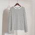 White and navy striped long-sleeve shirt on wooden hanger against white background