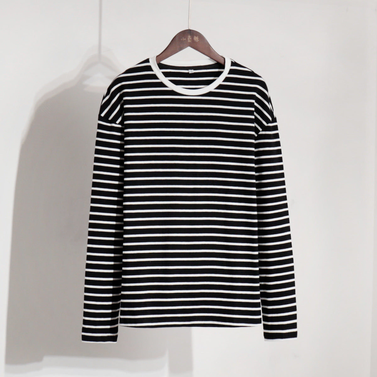 Black and white striped long-sleeve shirt hanging on wooden hanger