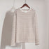 White and brown striped long-sleeve shirt on wooden hanger against white backdrop