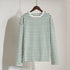 White and green striped long-sleeve shirt hanging on wooden hanger