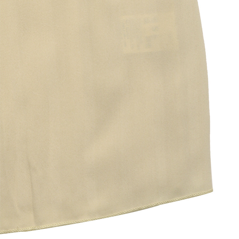 Detail shot of cream dress fabric showing smooth hemline finish