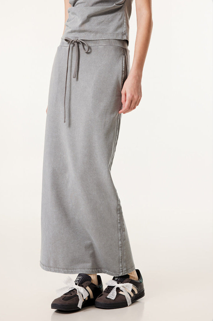 Long light gray denim skirt with soft drape and drawstring waist, worn with gray and black sneakers