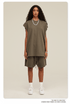 Model in olive green two-piece set with oversized tee and drawstring shorts, white sneakers and pearl necklace