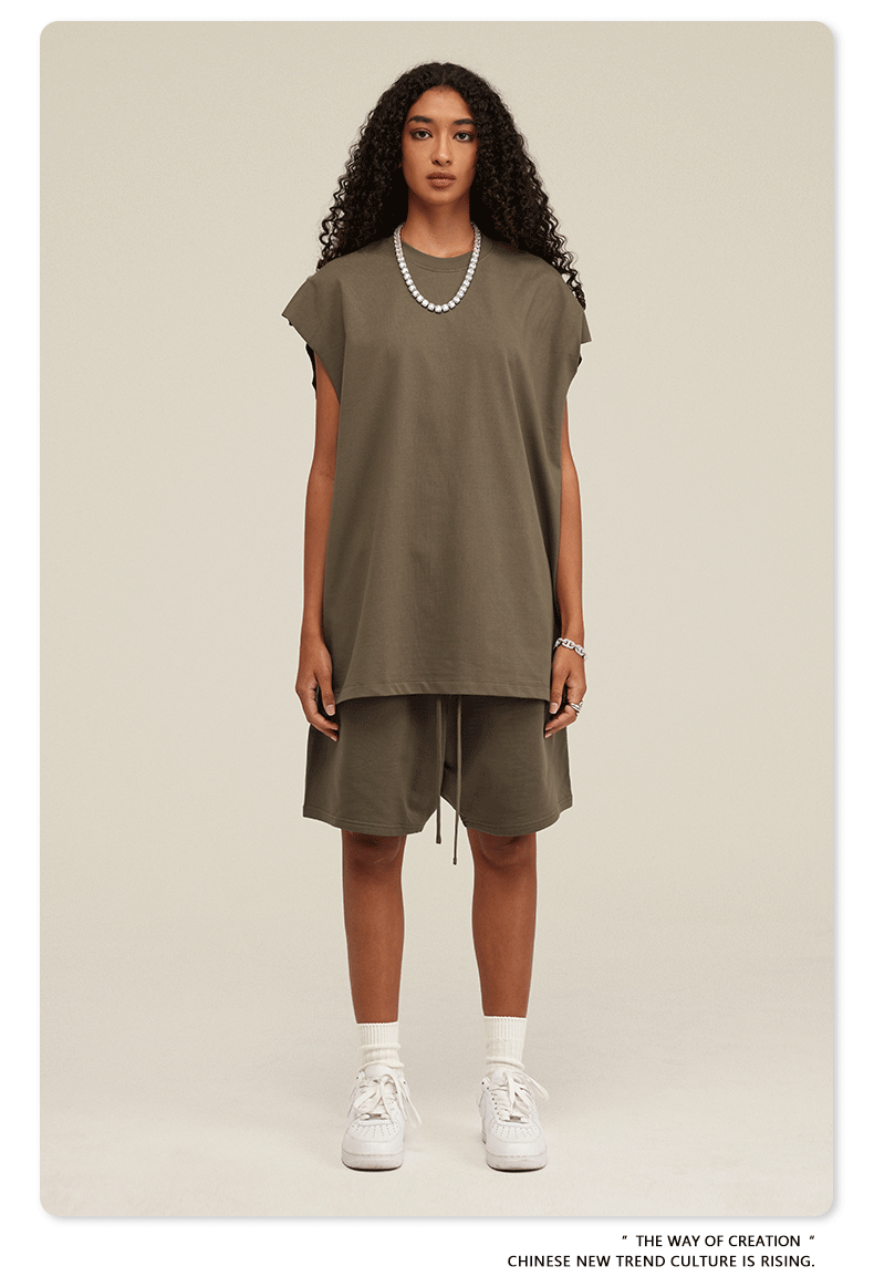Model in olive green two-piece set with oversized tee and drawstring shorts, white sneakers and pearl necklace