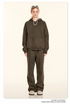 Blonde model wearing olive green oversized zip-up hoodie and matching sweatpants with white sunglasses on head, pearl necklace and beige shoes against cream backdrop