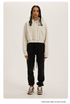 Cream and Black Two-Tone Outfit – Model in a cream cropped hoodie with black sweatpants and brown sneakers