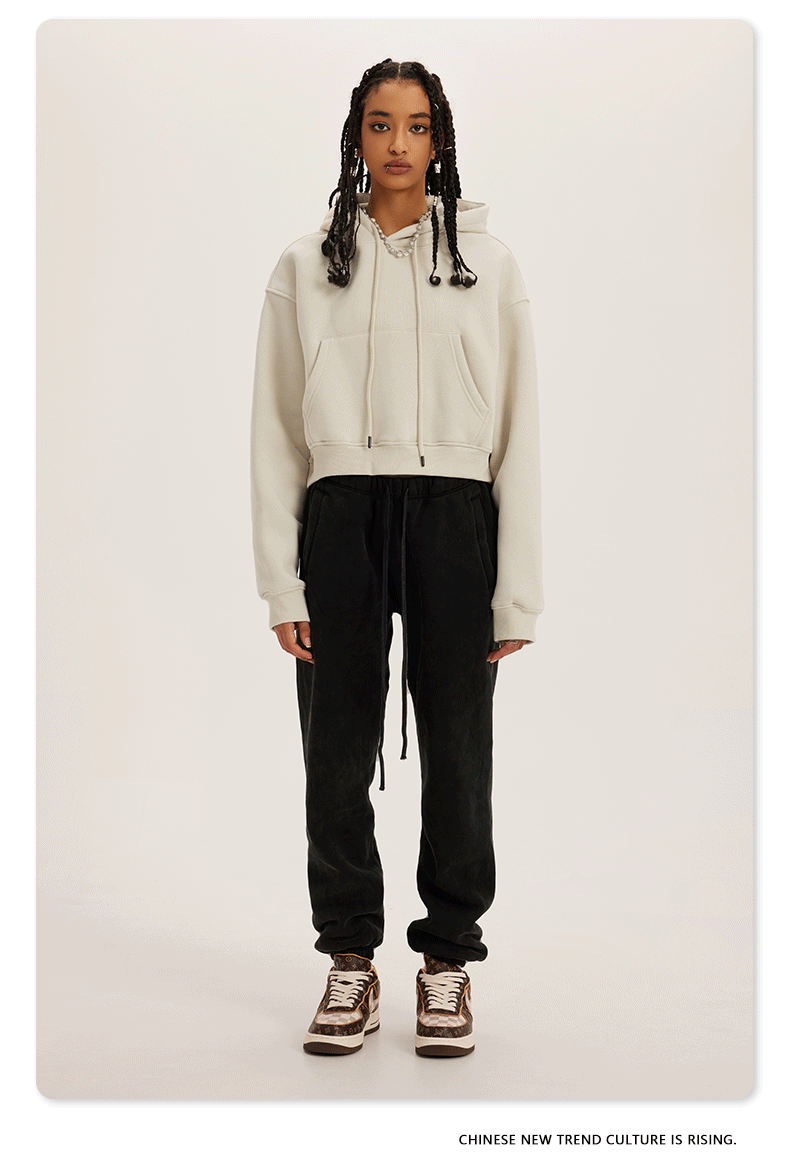 Cream and Black Two-Tone Outfit – Model in a cream cropped hoodie with black sweatpants and brown sneakers