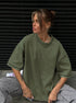 Person wearing an oversized green sweatshirt sitting against a black background