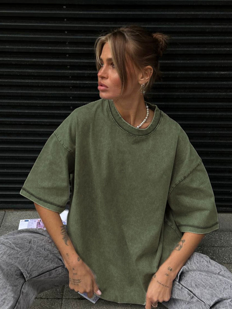 Person wearing an oversized green sweatshirt sitting against a black background
