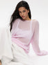 Light pink semi-sheer knit sweater with boat neckline and dropped shoulders, white camisole visible underneath