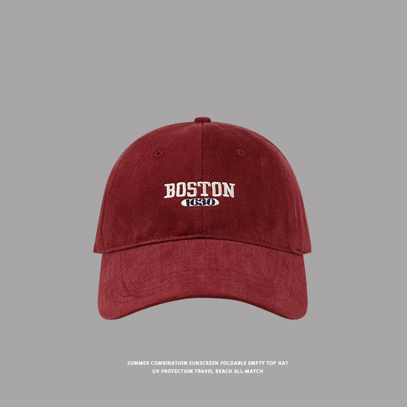 Close-up of wine red Boston cotton baseball cap with white embroidered logo, premium summer beach hat