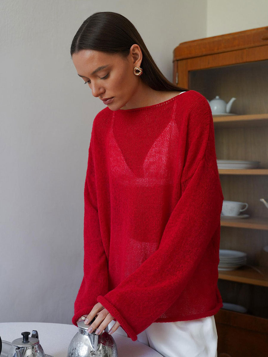 Red knit sweater with boat neckline and relaxed fit, styled with white pants, photographed in kitchen setting