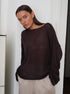 Dark brown oversized knit sweater with boat neck and relaxed silhouette, paired with cream colored pants