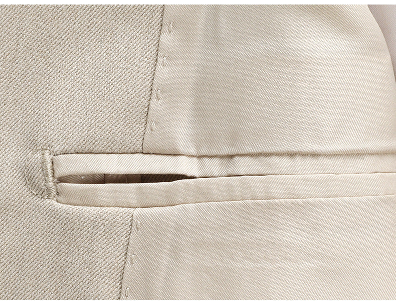 Detailed view of welt pocket construction on beige suit trousers