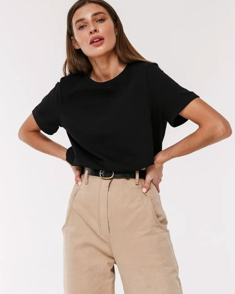 Black T-Shirt Outfit – Model wears a black short-sleeve T-shirt tucked into beige pants with a black belt