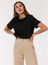 Black T-Shirt Outfit – Model wears a black short-sleeve T-shirt tucked into beige pants with a black belt