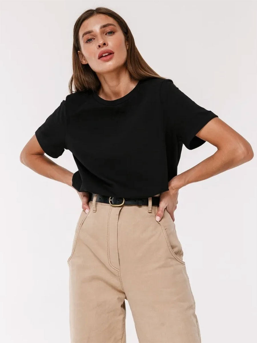 Black T-Shirt Outfit – Model wears a black short-sleeve T-shirt tucked into beige pants with a black belt