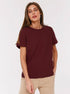 Burgundy T-Shirt Outfit – Model wears a burgundy short-sleeve T-shirt tucked into beige pants
