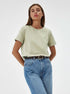 Pale Green T-Shirt Outfit – Model in a pale green T-shirt tucked into blue jeans, styled with a braided brown belt