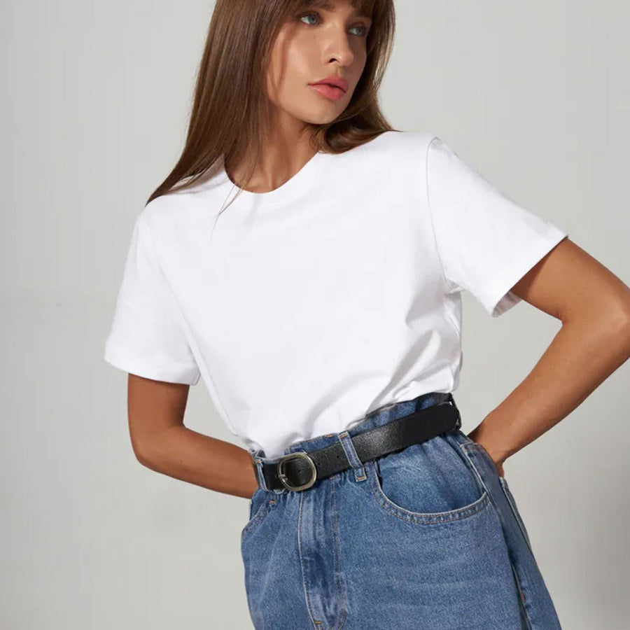 White T-Shirt Outfit – Model wears a white crew-neck T-shirt tucked into high-waisted blue jeans with a black belt