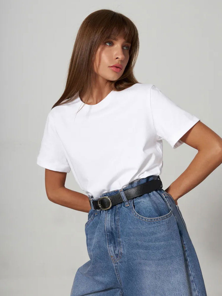 White T-Shirt Outfit – Model wears a white crew-neck T-shirt tucked into high-waisted blue jeans with a black belt