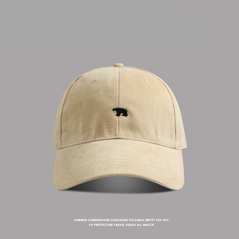Beige baseball cap with small black bear embroidery - A neutral beige dad hat with a subtle black bear emblem stitched at the center