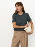 Dark Gray T-Shirt Outfit – Model in a dark gray short-sleeve T-shirt paired with beige pants, holding a cream handbag