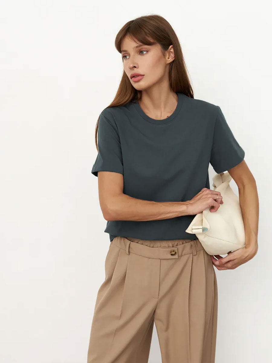 Dark Gray T-Shirt Outfit – Model in a dark gray short-sleeve T-shirt paired with beige pants, holding a cream handbag