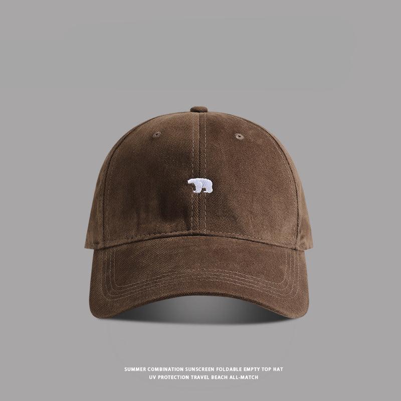 Brown baseball cap with small white bear embroidery - A warm brown dad cap featuring a white embroidered bear logo at the center