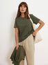 Olive Green T-Shirt Outfit – Model in an olive green T-shirt and beige sweatpants, carrying a cream tote and matching sweatshirt