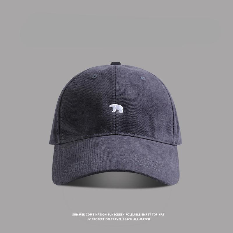 Navy blue baseball cap with small white bear embroidery - A dark navy dad hat featuring a small embroidered white bear logo