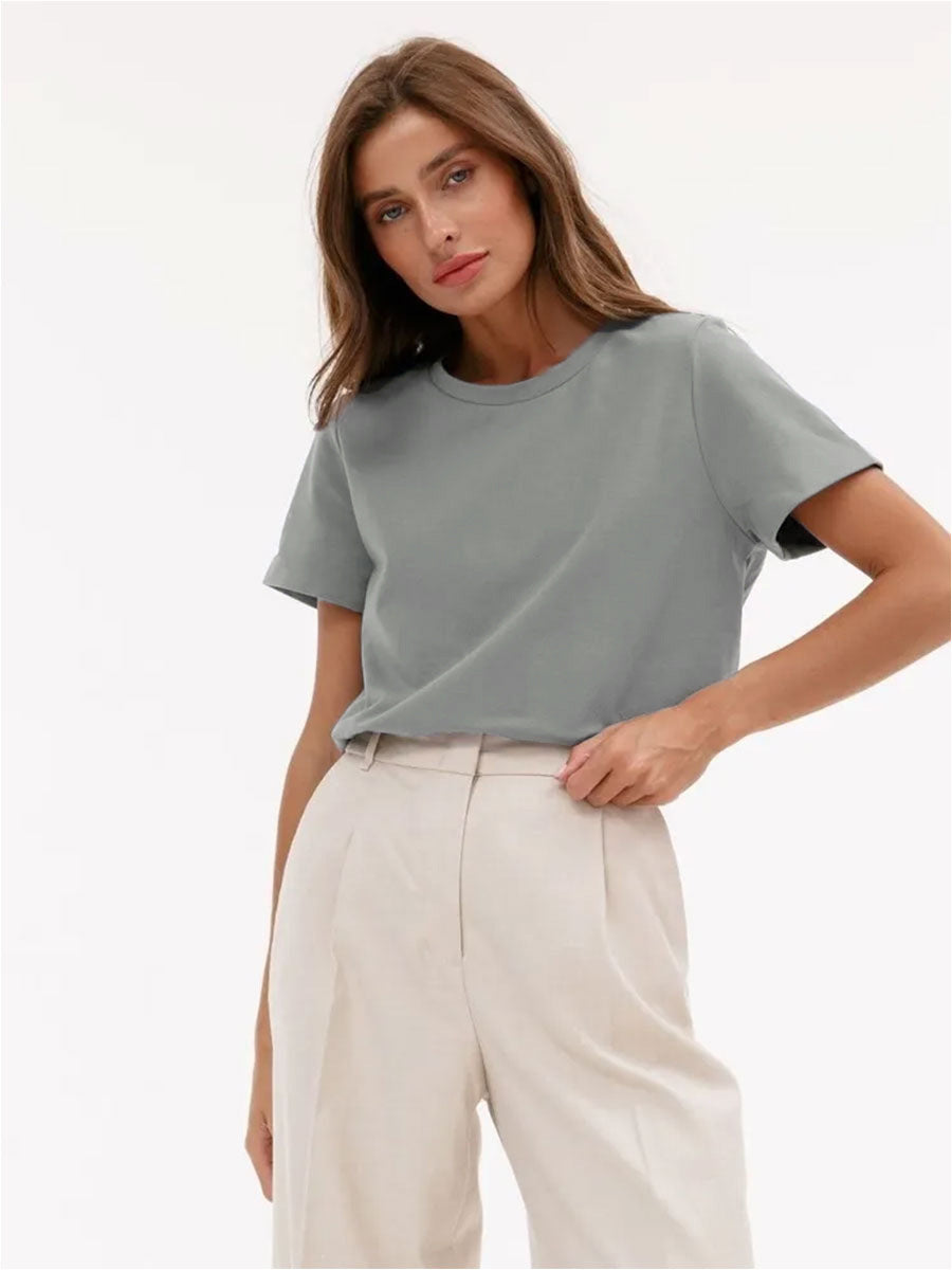 Muted Gray T-Shirt Outfit – Model wears a muted gray T-shirt with beige trousers, adjusting the waistband