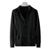 Black cable knit cardigan hanging on display with ribbed shawl collar, geometric knit pattern, and patch pockets clearly visible