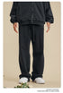 Front view of person in black zip-up hoodie and matching sweatpants on beige background with flower accents